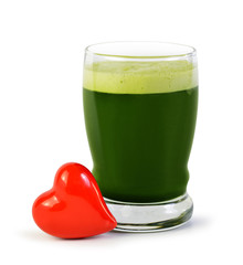 Green barley juice drink in glass and red heart isolated on white background. Detox superfood. The concept of healthy eating.