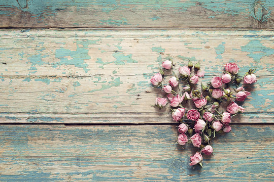 Fototapeta Heart from dried rose flowers on the turquoise old wooden background with copy space. Flowers composition.