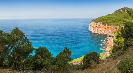 Fototapeta na wymiar Idyllic Mediterranean landscape with a solitary bay of azure color and mountains covered with pine forest, travel in paradise concept