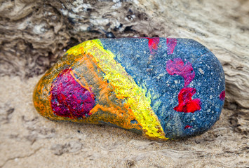 Abstract of a painted stone on a beach.