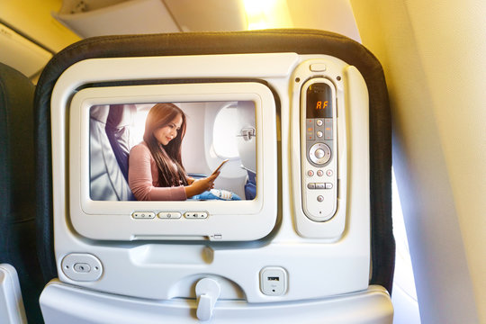 Passenger seat of plane with screen image beautiful asian woman use of mobile phone inside airplane