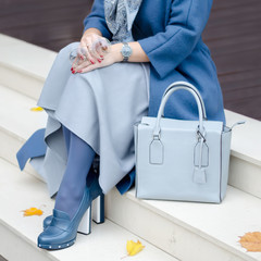 Beautiful fashionable shoes on women's leg. Stylish  ladies accessories. blue shoes and bag, coat...