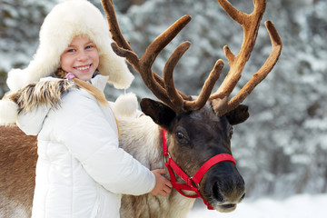 Winter playtime.Happy little girl hugging her reindeer.