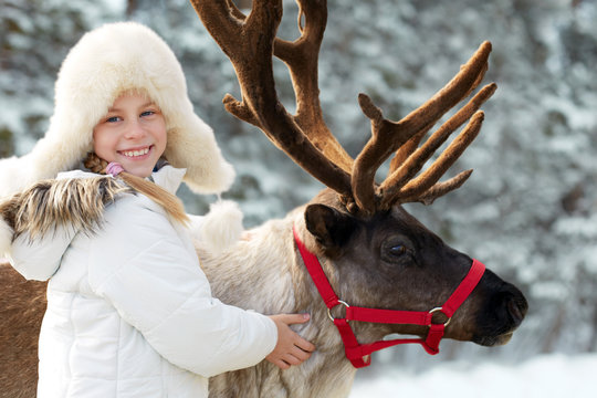 Winter playtime.Happy little girl hugging her reindeer.