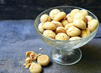 Italian Christmas cookies amaretti in a white heart shaped bowl.Tasty Italian amaretti biscuits on old wooden table.Amarettini cookies.Selective focus.