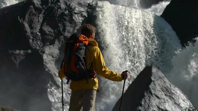 Backpacker watches a waterfall in slow motion.