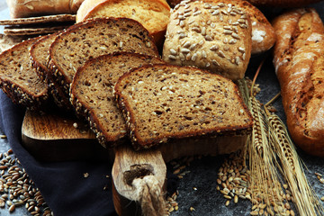 Sliced rye bread on cutting board. Whole grain rye bread and rolls with seeds.
