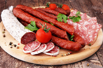 Food tray with delicious salami, pieces of sliced ham, sausage, tomatoes, salad and vegetable - Meat platter with selection - Cutting sausage and cured meat