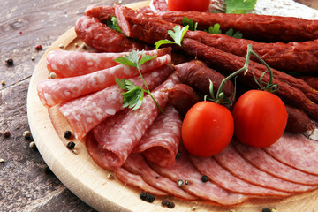 Food tray with delicious salami, pieces of sliced ham, sausage, tomatoes, salad and vegetable - Meat platter with selection - Cutting sausage and cured meat