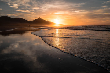 Amazing beach sunset with endless horizon and hills, reflection in the background