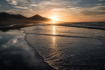 Amazing beach sunset with endless horizon and hills, reflection in the background