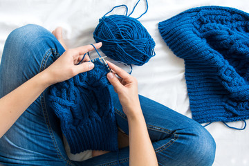 Woman knitting blue sweater. Overhead shot