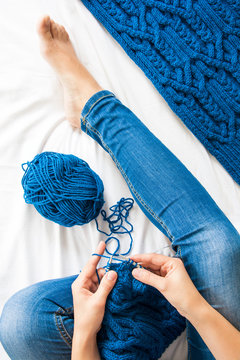 Woman knitting blue sweater. Overhead shot