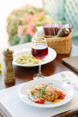 Italian food - delicious lasagne in white plate on table with red wine.