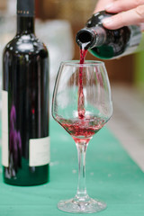 Sommelier pouring the glass with red wine.