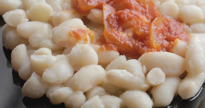 Fagioli bianchi con salsa al pomodoro piccante e cipolla su un piatto nero