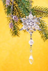 Christmas crystal decoration on xmas tree on yellow background with copy space.