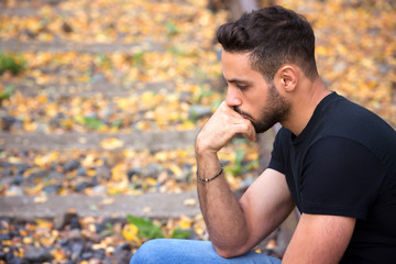 handsome man sitting on train tracks and looking pensive