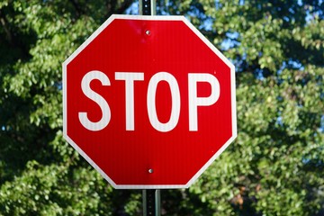 The red stop sign with the leaves in the background and on a close up view.