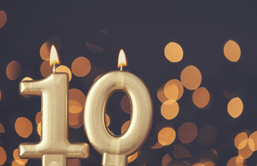 Gold number 10 celebration candle against blurred light background