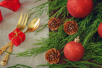 Christmas table setting, appliances fork spoon and decorative napkin with pine cones and fir branches on a wooden background with copy space