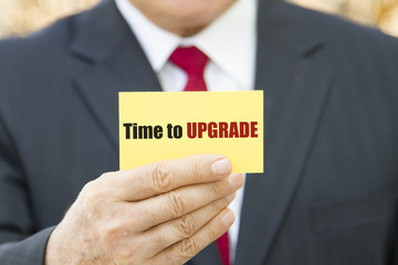 Obraz premium Businessman showing a card with text TIME TO UPGRADE