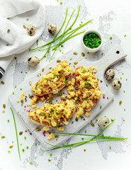 Homemade Quail Scrambled eggs on crispy toast, bread with green onion, chives on white board.