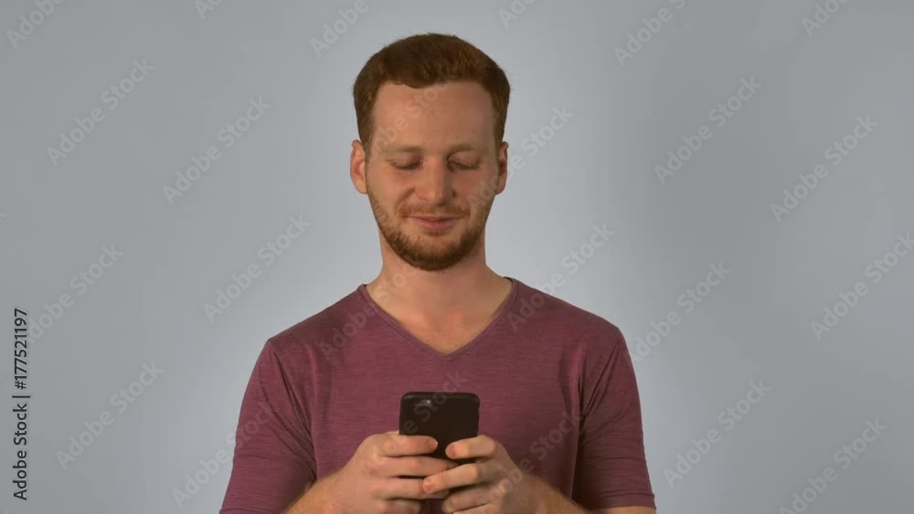 Poster caucasian young man using smartphone. happy smiling student texting or chatting with friend via inte