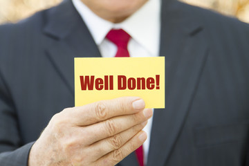Businessman showing a card with text WELL DONE.