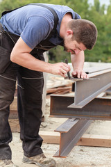 A man marks a metal product before cutting