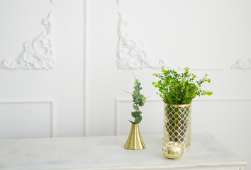 Brass golden candlestick. Green decorative plants in brass vase