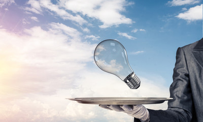 Hand of waitress presenting lightbulb on tray.