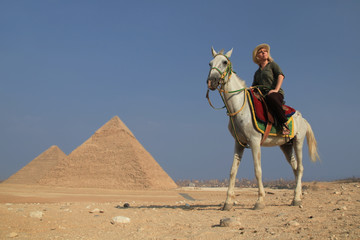 Froschperspektive von Frau auf Pferd, alleine vor den Pyramiden