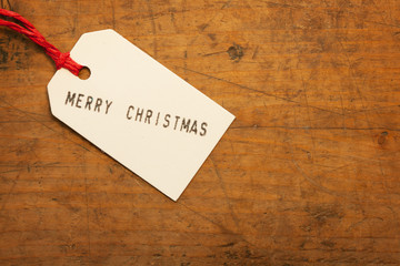 Merry Christmas tag on old wooden surface.
