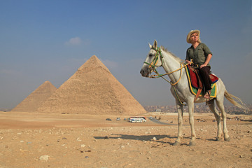 blonde Frau auf weißem Pferd vor den Pyramiden, Hintergrund Kairo