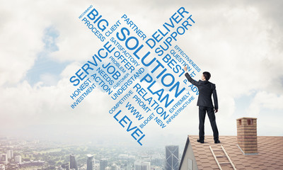 Young businessman standing on house roof and writing leadership 