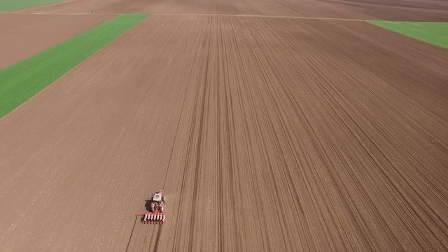 Aerial shot of a farmer seeding, sowing crops at field.