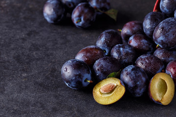 Plums and plums slices on dark background copy space.