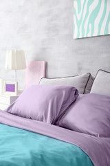 Lilac accent in modern interior. Comfortable bed with pillows in room