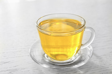 Glass cup with oil on light wooden background