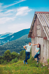 Beautiful young couple near old wooden house in the mountain peak