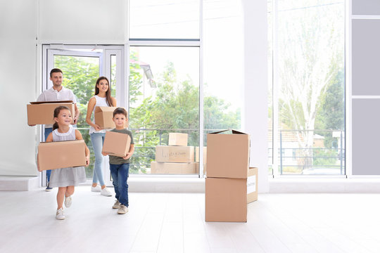 Happy family with moving boxes entering new house