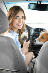 Beautiful young woman with cute dog in car