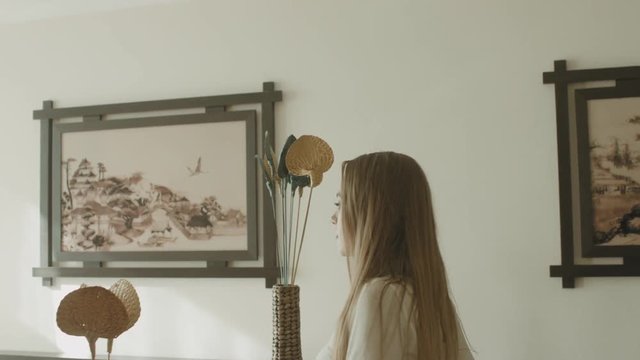 Beautiful girl with long hair standing next to the bed in the hotel room