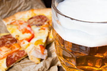 Light beer in glass and fragrant Italian pizza.