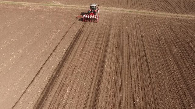 Aerial shot of a farmer seeding, sowing crops at field.