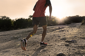 sport man with ripped athletic and muscular legs running uphill off road in jogging training workout