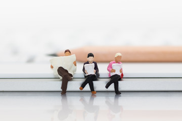 Miniature people sitting on keyboard using as background education or business concept.