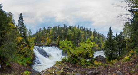Fototapeta na wymiar Cliff, stone wall, forest, waterfall and wild river panoramic view in autumn. Fall colors - ruska time in Myllykoski. Karhunkierros Trail, Oulanka National Park in north Finland. Lapland, Europe
