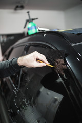 Car tinting - Worker applying tinting foil on car window. 